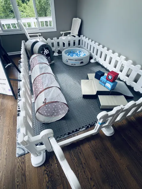 Classic soft play setup with white fence, foam tunnel, ball pit and ride-on toys