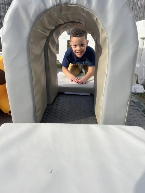 A child peeking through a soft foam tunnel